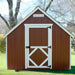 Red little cottage co firehouse playhouse kit with white trim and door in a garden setting