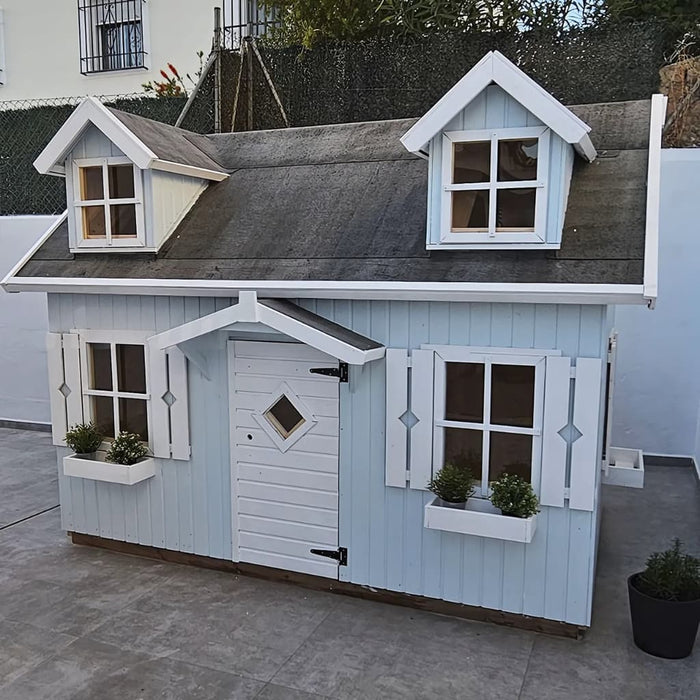 Light blue palmako 9x6 marie children's playhouse with white accents on a concrete patio