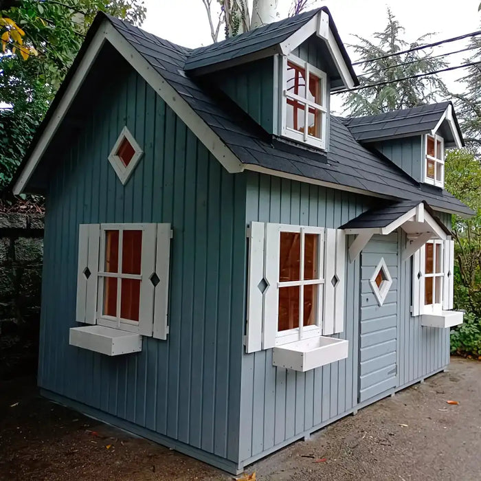 Children's palmako marie 9x6 playhouse with a blue exterior and white trim in a natural setting