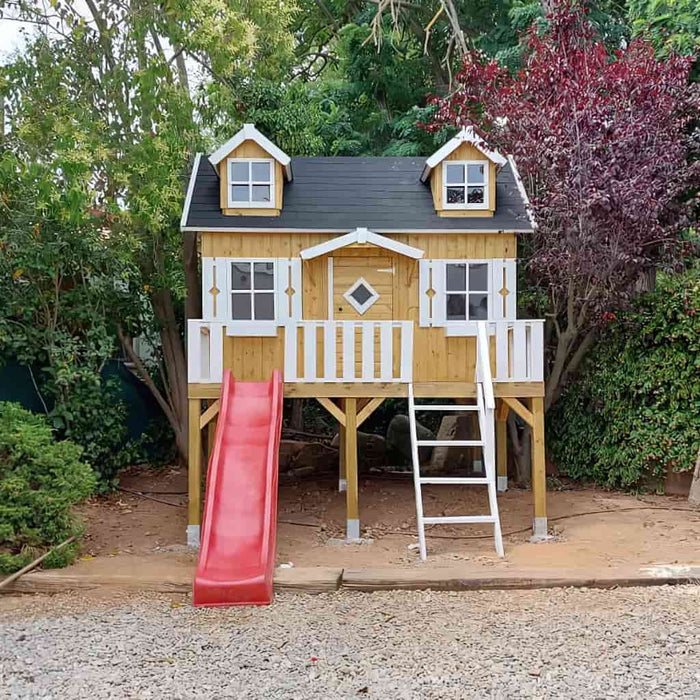 Wooden palmako marie 9x6 playhouse with a red slide and white ladder in a garden setting