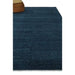 Full view of the Midnight Blue hand-knotted wool rug styled with an ottoman
