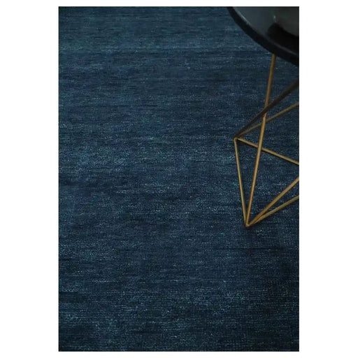 Partial view of the Midnight Blue hand-knotted wool rug styled beside a chair