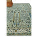Angled view of the Moss Green and Ivory Tree of Life rug showing its floral and vine pattern, with part of brown furniture visible at the upper edge.