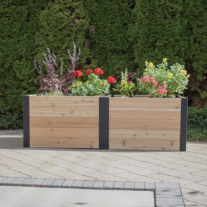 Outdoor Living Today 6x3 Urban Raised Garden Bed with flowers on a paved area with greenery in the background