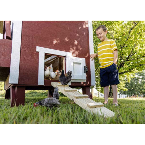 Classic red OverEZ Large Chicken Coop with chickens using the ramp beside a child.