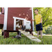 Classic red OverEZ Large Chicken Coop with chickens using the ramp beside a child.