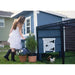 Girl beside a blue Coastal OverEZ Large Chicken Coop and attached chicken run.