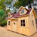 Wooden palmako marie 6x9 playhouse with dormer windows in a natural setting
