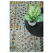 Top-down room-context view of the rug beside a round dark table and plant