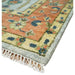 Close-up of a rug corner showing the rust border, bound edge, and white fringe