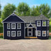 Navy blue Little Cottage Co. Sara's Victorian playhouse with white trim in a garden setting