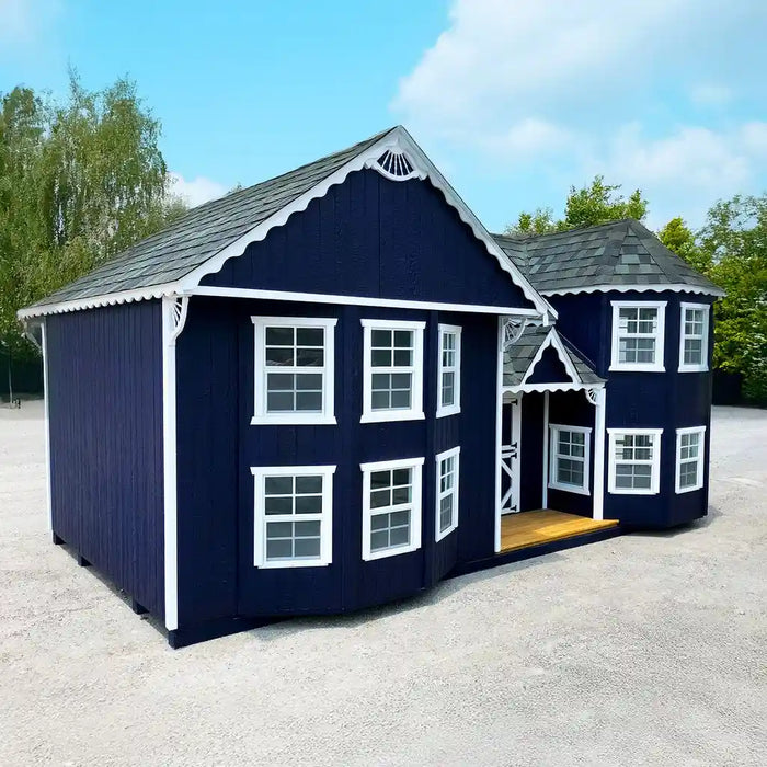 Navy blue Little Cottage Co. Sara's Victorian playhouse with white trim on a gravel surface with trees in the background