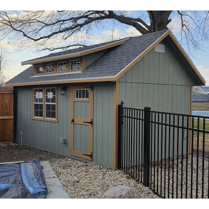 EZ-Fit Skyview Shed Kit with wooden door and windows, surrounded by gravel and a tree in the background.