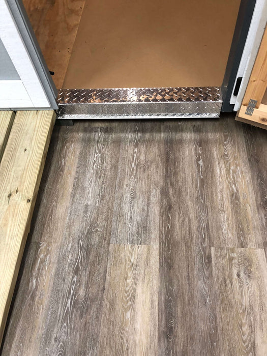Close-up of vinyl flooring inside the 10x14 EZ-Fit Riverside shed kit, leading to a sturdy wooden ramp for easy access