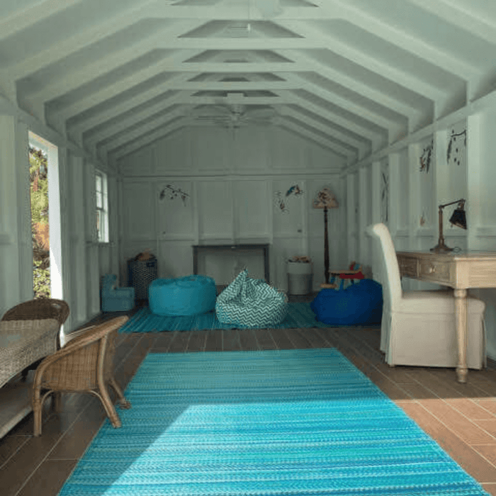 Spacious interior of a modern shed featuring a high vaulted ceiling, wooden floor, and ample natural light, perfect for a creative studio.